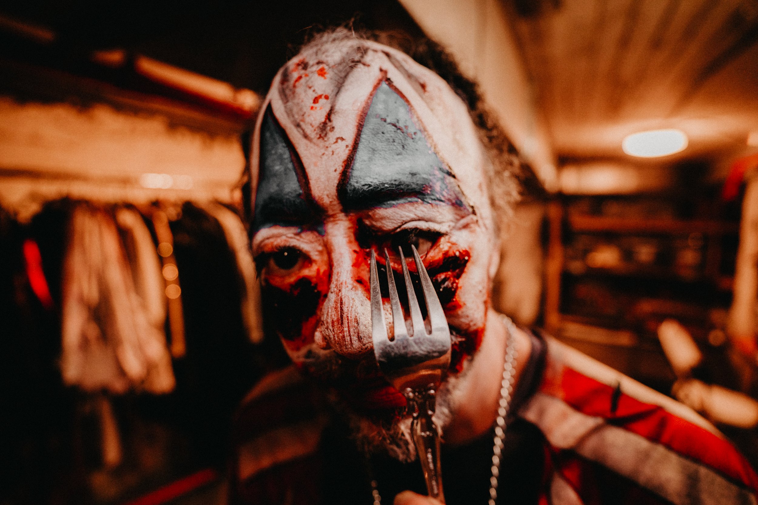 A man with a clown-like face paint brandishing a knife, showcasing a theatrical and potentially menacing appearance at New York City's Blood Manor, one of the top haunted houses in the USA