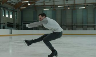 A figure skater performing a controlled spin inside an indoor rink, showcasing skill and balance on the ice.