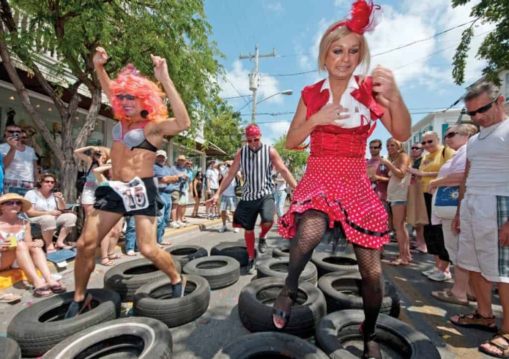 Men in eccentric drag attire participating in Key West's Conch Republic Drag Race, part of the Conch Republic Independence Celebration in April, a vibrant LGBTQ+ event.