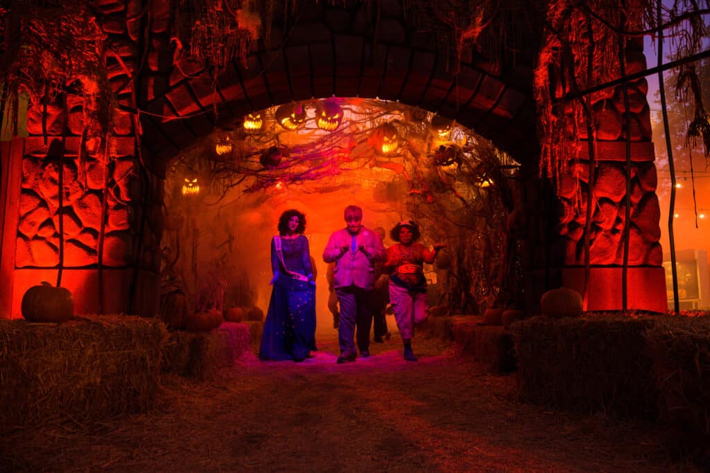 A crowd of individuals strolling through a Halloween-themed area at the Los Angeles Haunted Hayride