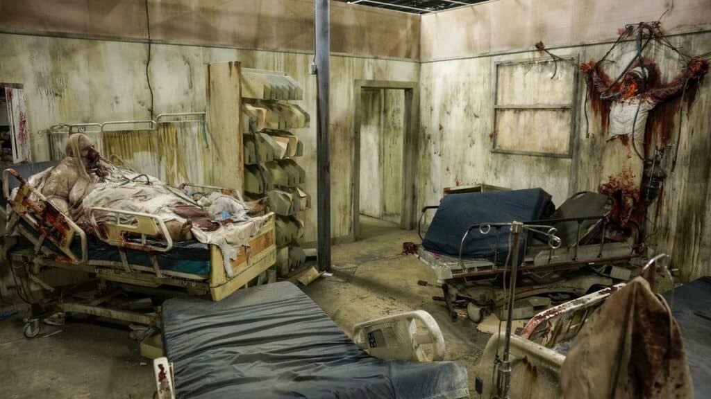 A hospital room in disarray, featuring blood and scattered items on the floor, within the eerie setting of "The House of Torment," one of the top haunted houses in the USA.