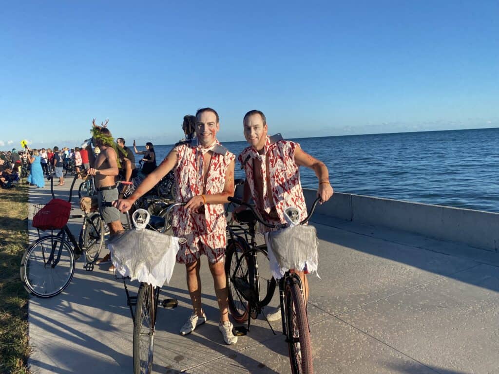 Two men wearing identical bloody shirts and shorts for Fantasy Fest's Zombie Bike Ride.