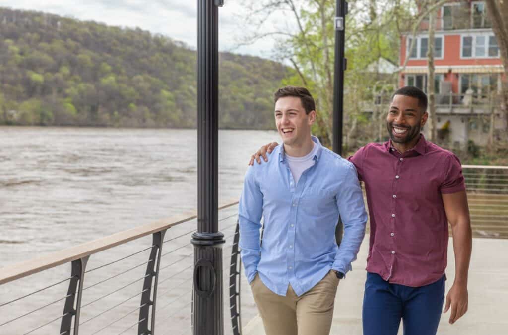 Two men walking along Delaware River in New Hope, PA, Bucks County - Embracing while enjoying the scenic riverfront.