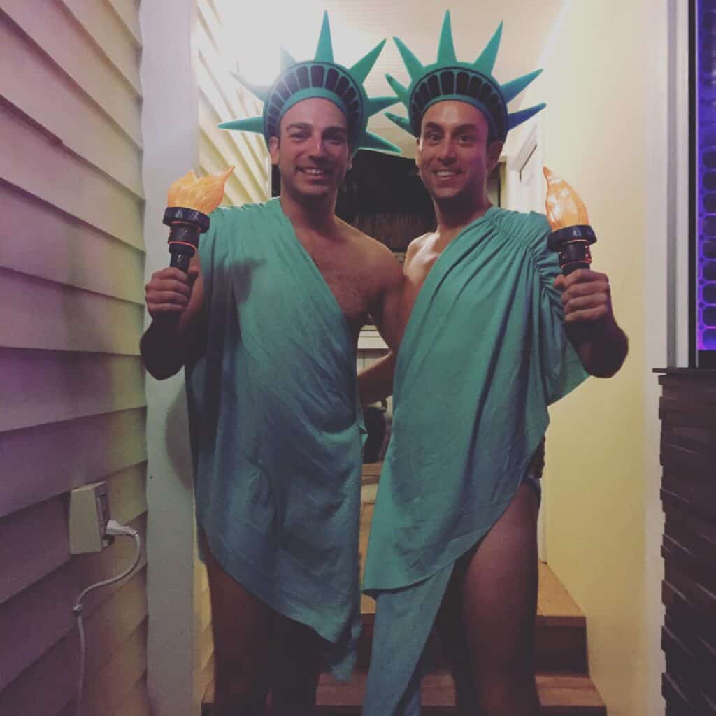 Two men draped in green garments resembling the Statue of Liberty for a travel-inspired Halloween costume