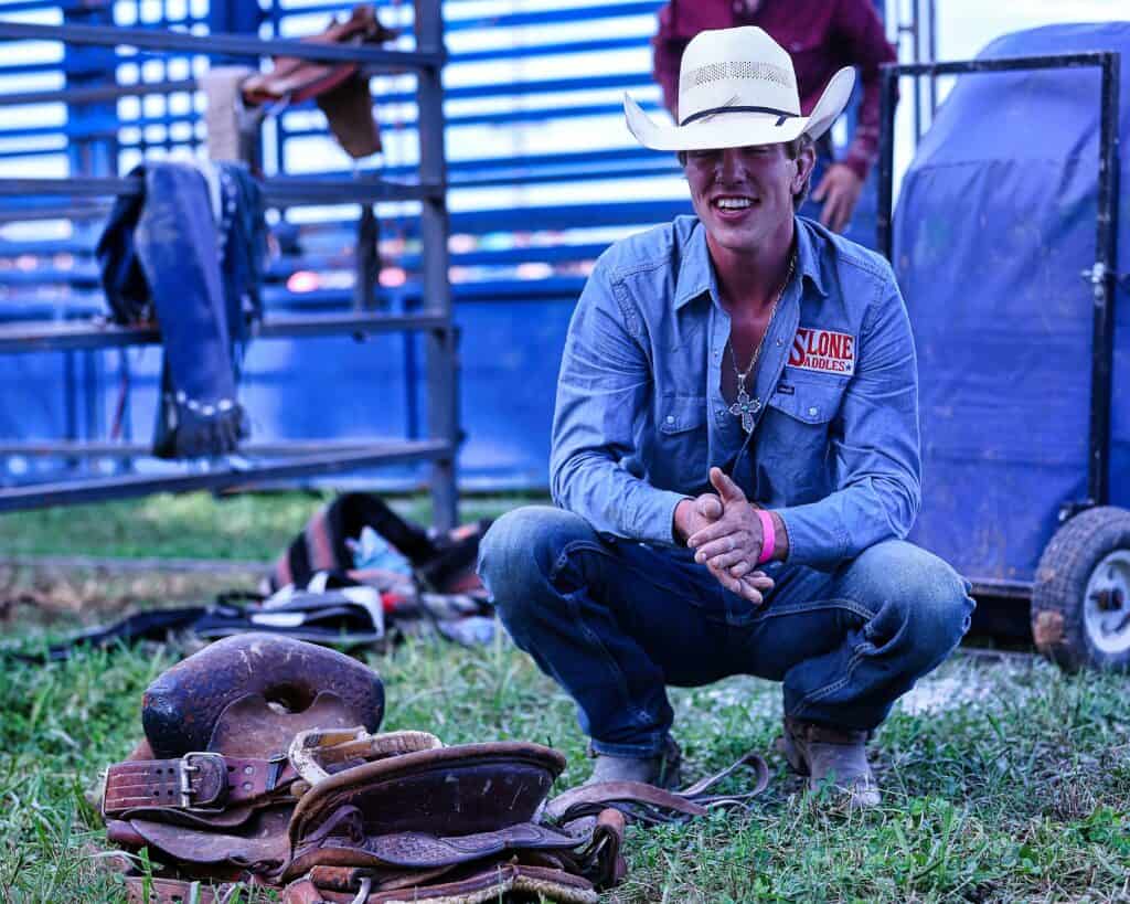 A smiling cowboy looks over his saddle at IGRA World Gay Rodeo Finals 