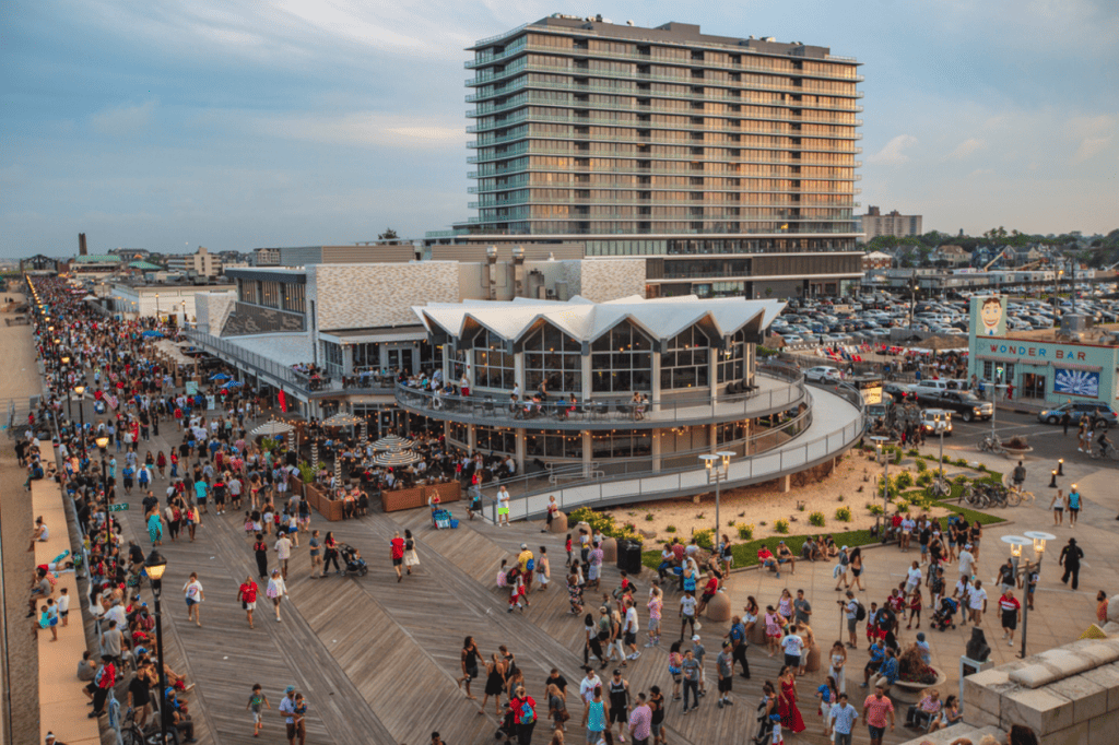 Busy Asbury Park boardwalk with Wonder Bar in the distance, showcasing vibrant atmosphere and iconic landmarks.