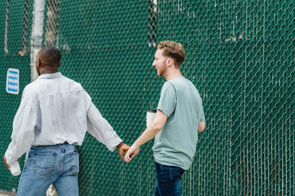 Interracial male couple holding hands, symbolizing love and diversity in relationships.