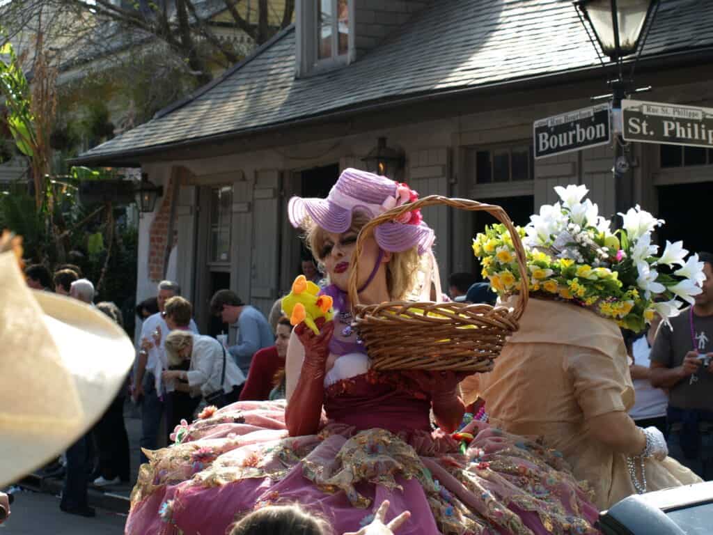 Drag queen riding in a convertible car at the New Orleans Gay Easter Parade, a festive celebration during Easter in a LGBTQ+-friendly destination.