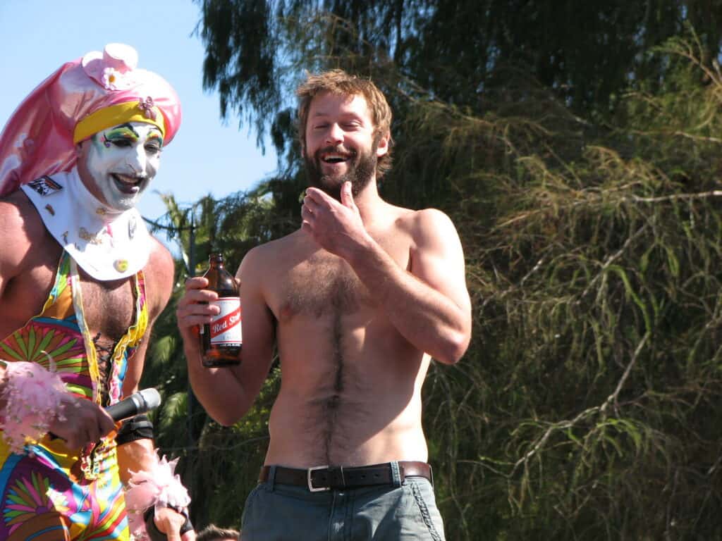 A shirtless male contestant poses with a member of The Sisters of Perpetual Indulgence at the Hunky Jesus and Foxy Mary contest in San Francisco, celebrating diversity and inclusivity in the LGBTQ+ community.