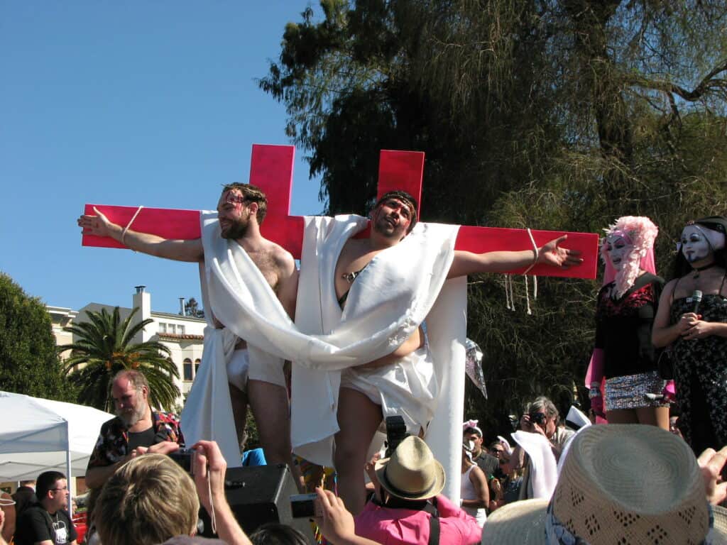 Two participants portray Jesus on the cross at the Hunky Jesus and Foxy Mary contest in San Francisco, a celebration of diversity and inclusivity in the LGBTQ+ community.