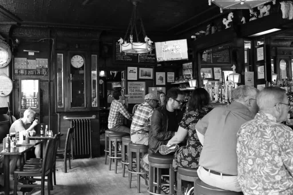 Interior shot of patrons seated on barstools at the historic White Horse Tavern, a renowned literary haunt on the Truman Capote NYC tour