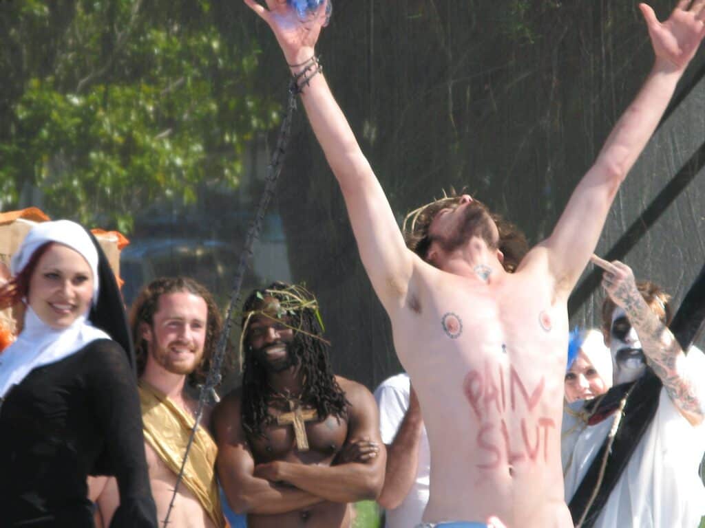A shirtless male contestant participates in the Hunky Jesus and Foxy Mary contest in San Francisco, surrounded by onlookers, celebrating diversity and inclusivity in the LGBTQ+ community.