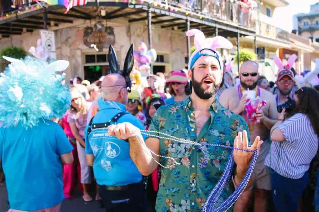 Man wearing bunny ears holding Mardi Gras beads in New Orleans, a festive image representing LGBTQ+ Easter celebrations and gay-friendly getaways.