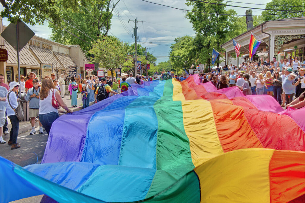 Rainbow flag waving down Main Street during New Hope Celebrates Gay Pride parade, symbolizing diversity and inclusion in spring LGBTQ+ pride events.
