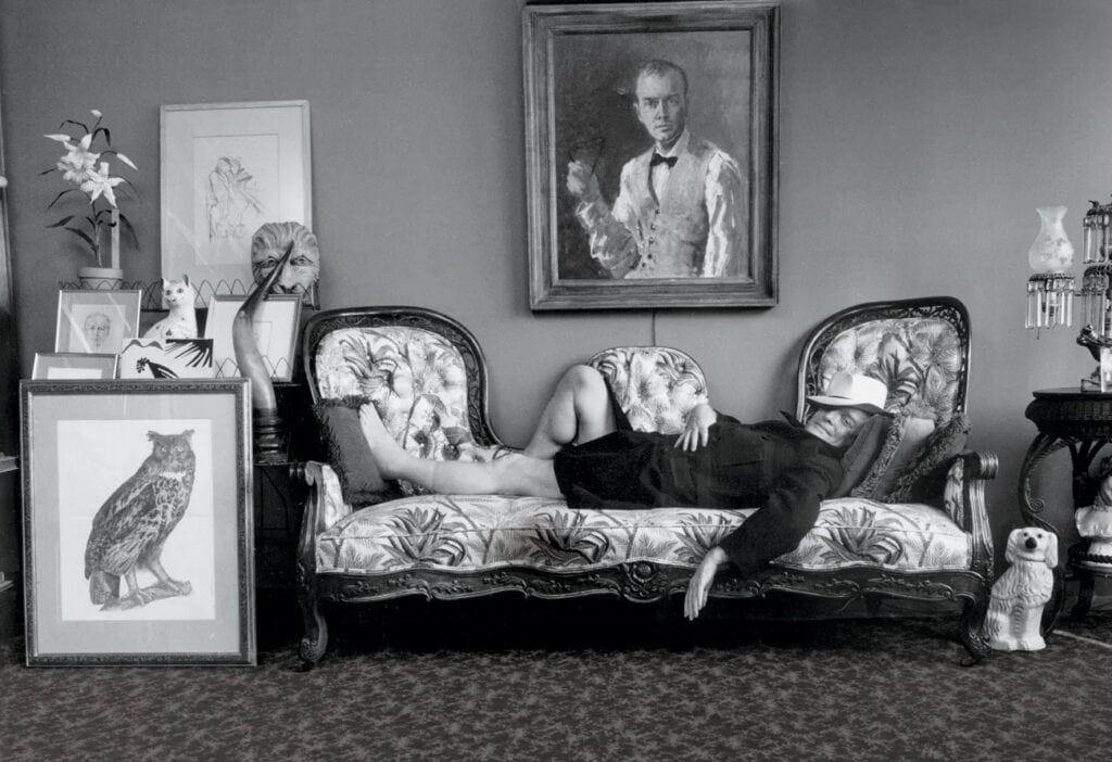 Truman Capote relaxing on the sofa at his historic brownstone in Brooklyn Heights, capturing the essence of his literary lifestyle