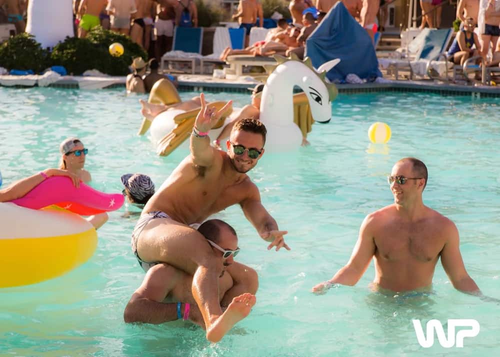 Men enjoying a pool party at White Party in Palm Springs, California, a popular LGBTQ+ event.