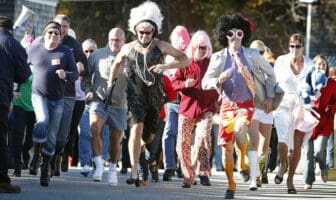 Runners in colorful costumes racing in the OgunquitFest High Heel Dash at Perkins Cove