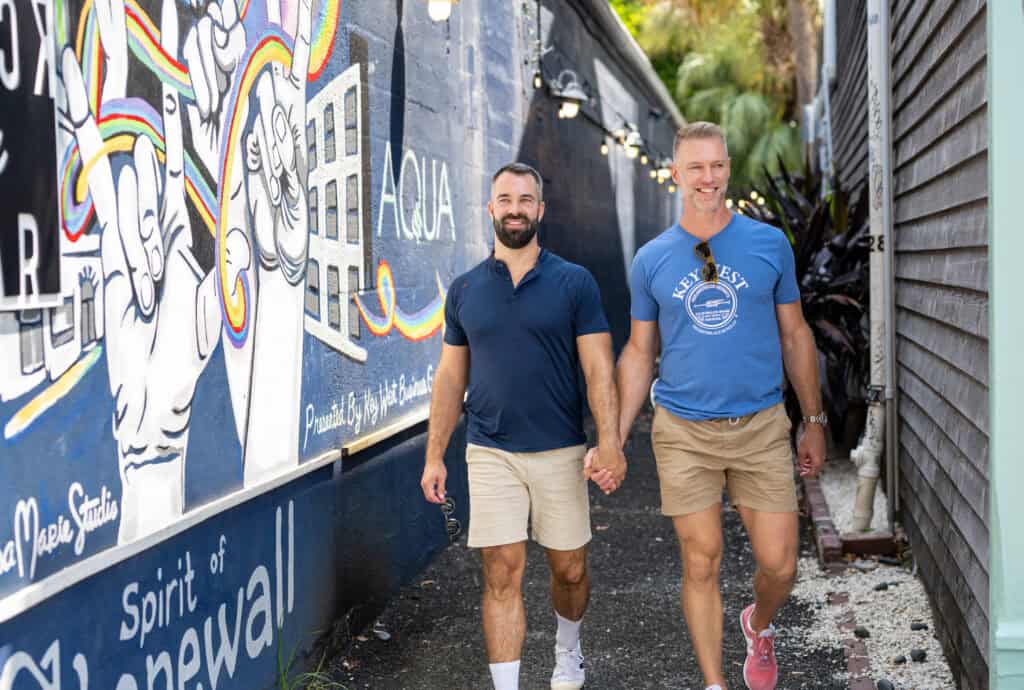 Two men walking hand in hand on a colorful street in Key West.
