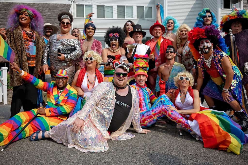 A lively group of people dressed in colorful outfits and rainbow accessories, celebrating Provincetown LGBTQ+ events together.