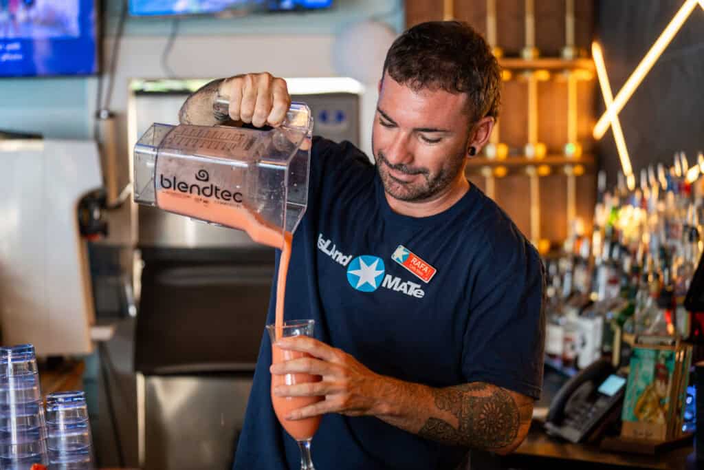 A bartender pours a pink smoothie from a Blendtec blender into a glass at the cafe in the Island House Key West.