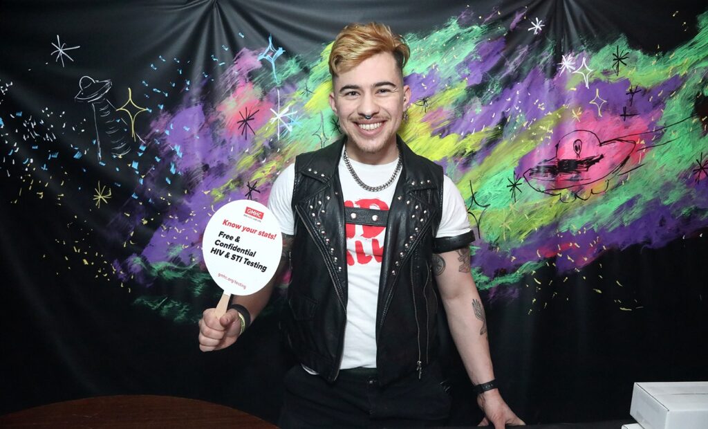 Smiling volunteer promoting free HIV and STI testing, showing the health side of safety in gay travel peak sluttiness culture.