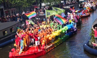 Amsterdam Pride Canal Parade boat with rainbow flags and balloons, symbolizing the Trump LGBTQ exodus abroad.