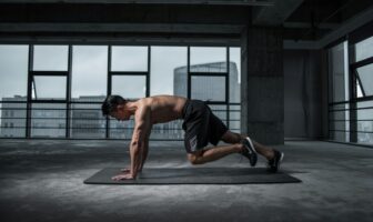Athlete doing mountain climbers in a modern gym, boosting endurance as part of a pre vacation workout routine.