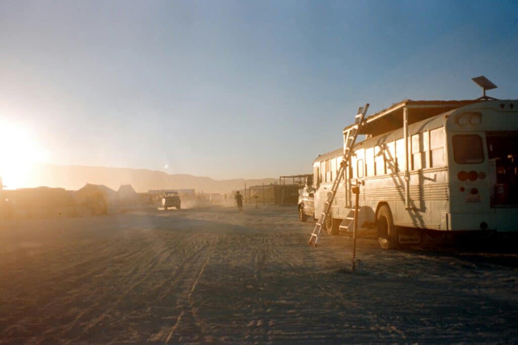 A converted bus at Burning Man during sunrise, illustrating the van life to buslife trend in festival culture.