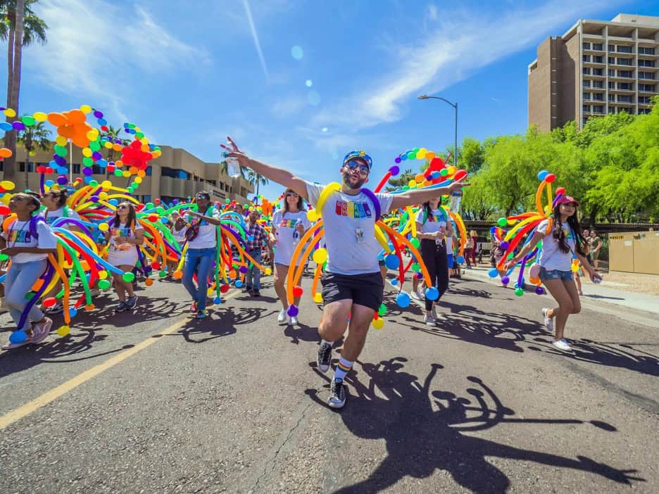 Marchers dressed in rainbow balloon costumes at Phoenix Pride parade, celebrating together during fall Pride events 2025.