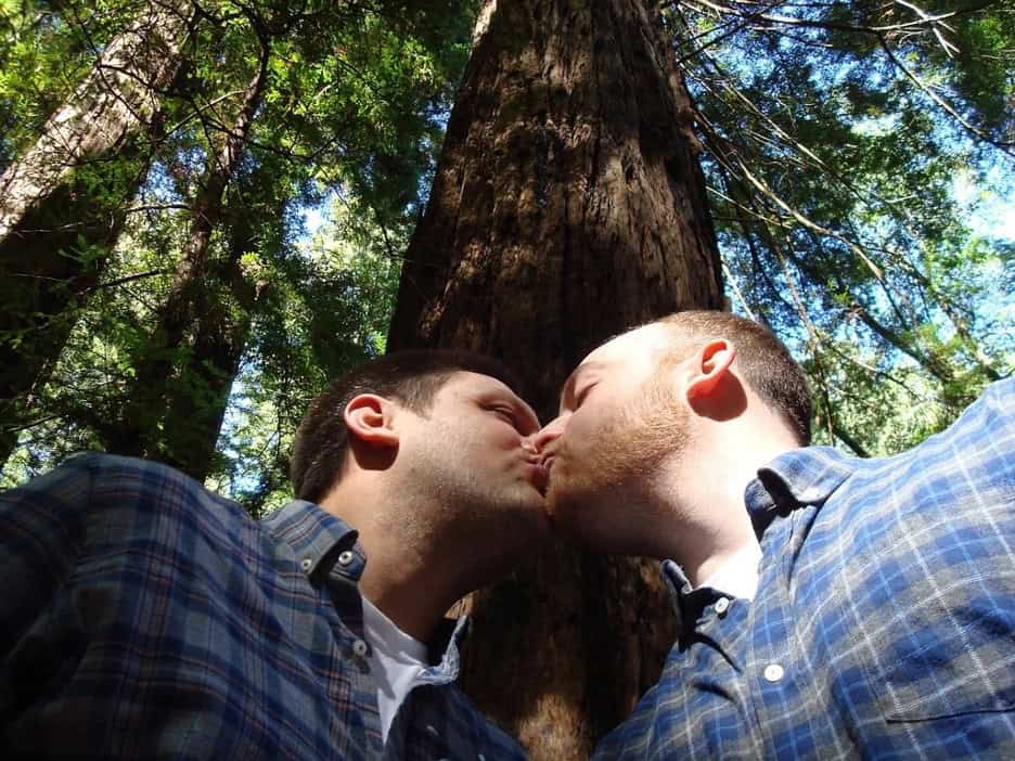 A couple kisses under tall trees, symbolizing freedom and nature as part of London top gay cruising experiences.