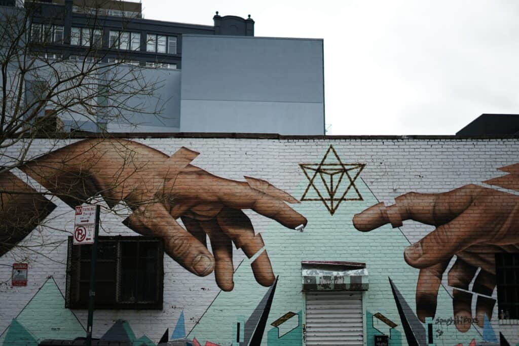 Street mural of two hands reaching toward a Star of David, symbolizing reflection and renewal during gay travel Jewish holidays.