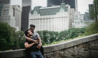 Romantic gay couple embracing in Central Park, New York City, proving cheap gay travel can be intimate and urban.