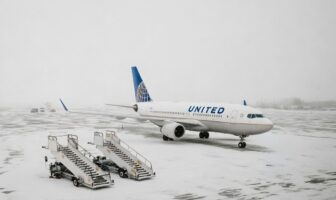 Commercial airplane sits grounded on a snow-covered runway as winter weather disrupts flights.