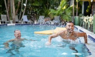 Guests enjoying a lively pool moment at Island House Key West, with water splashing and a relaxed social atmosphere
