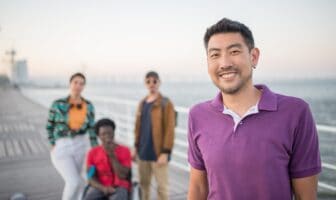 Diverse group of friends enjoying a waterfront boardwalk while planning their next summer adventure.