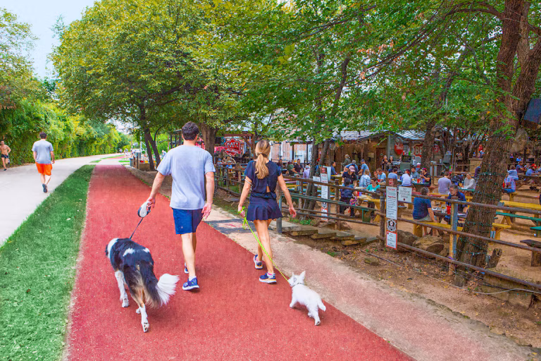 Gay Dallas Travel Guide featuring people walking dogs along Katy Trail beside Katy Trail Ice House.