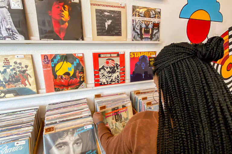 Gay Dallas Travel Guide featuring a shopper browsing vinyl records at Spinster Records in Bishop Arts.