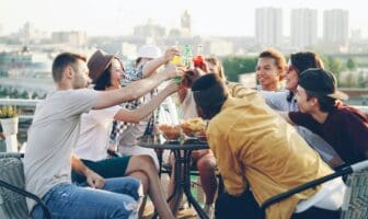 Friends raising drinks on a rooftop overlooking the city, celebrating LGBTQ group travel experiences.