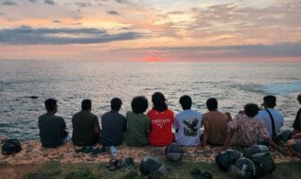 Gay group travel lessons unfold as a group of friends watches the sunset together along the ocean.